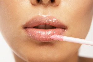 Young woman applying pink lipgloss --- Image by © Mario Castello/Corbis